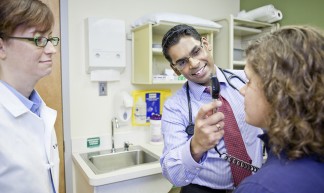 Doctors and residents working with patients at the JFK clinic in St. Louis. Satish Chandraprakasam, MD; Nikole Forget, MD in the background - Mercy Health