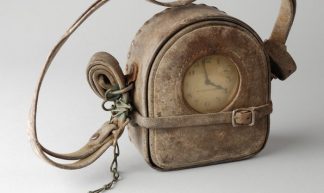 Prikklok van nachtwaker met leren omhulsel, riem en met sleutel aan ketting, gehaald uit puin 1940 - Museum Rotterdam